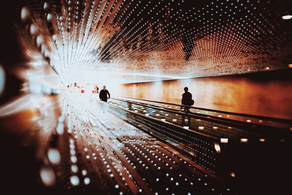 people walking through tunnel with light at the end